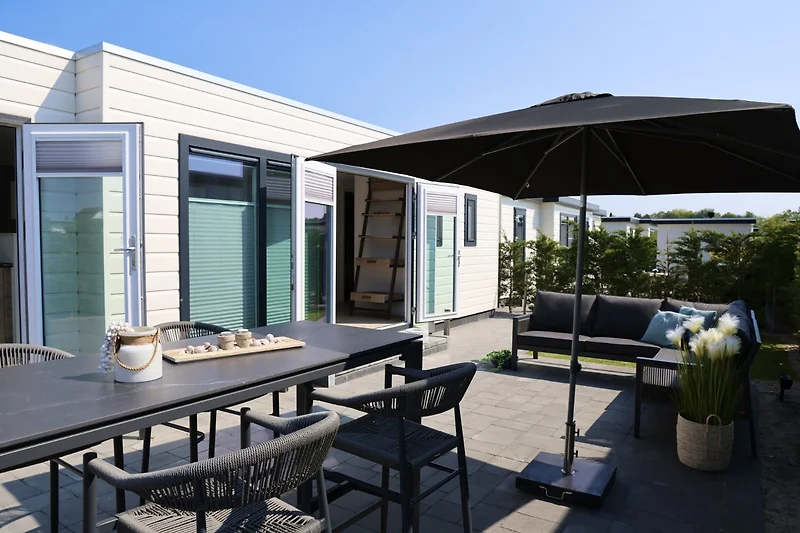 Großzügige Terrasse mit Sitzgruppe, Esstisch, Pflanzen und Sonnenschutz.