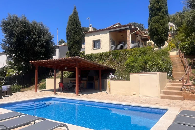 Villa mit Pool, Sonnenschirmen und gemütlichen Liegestühlen.