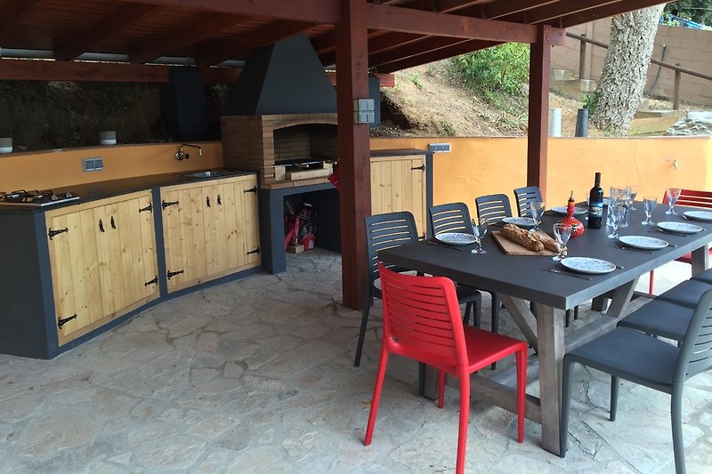 Outdoor kitchen under patio with gas stove, fridge and BBQ