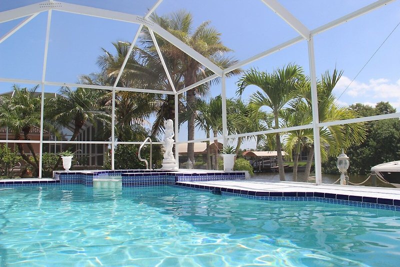 Schwimmbecken mit Sonnenliegen und Blick auf das azurblaue Wasser. Perfekt für Entspannung und Freizeit.