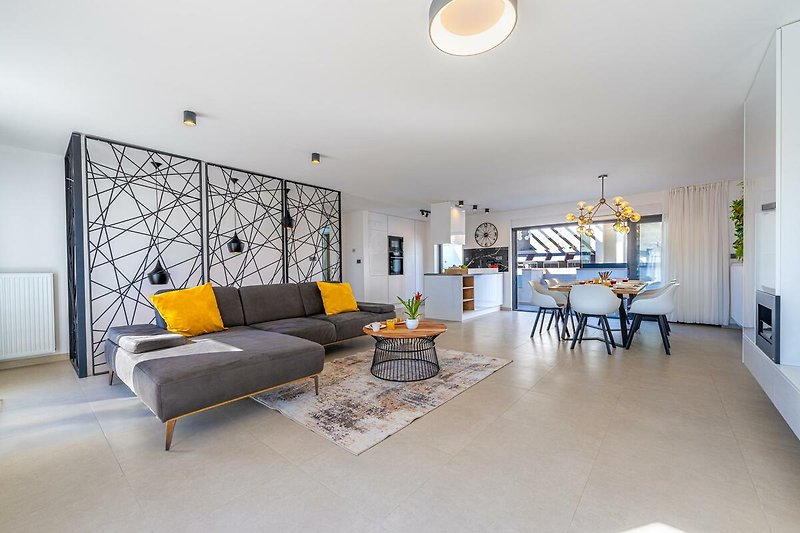 Stilvolles Wohnzimmer mit Holzmöbeln, gemütlicher Couch und moderner Beleuchtung.