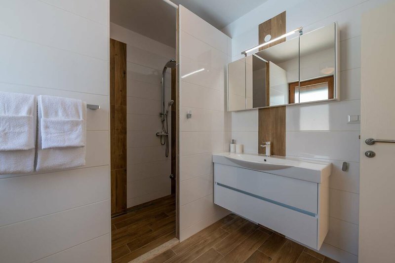 Schönes Badezimmer mit Holzboden, Spiegel und modernem Waschbecken.