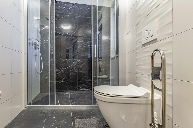 Moderne Badezimmerausstattung mit stilvollem Duschpaneel und Glasduschtür.