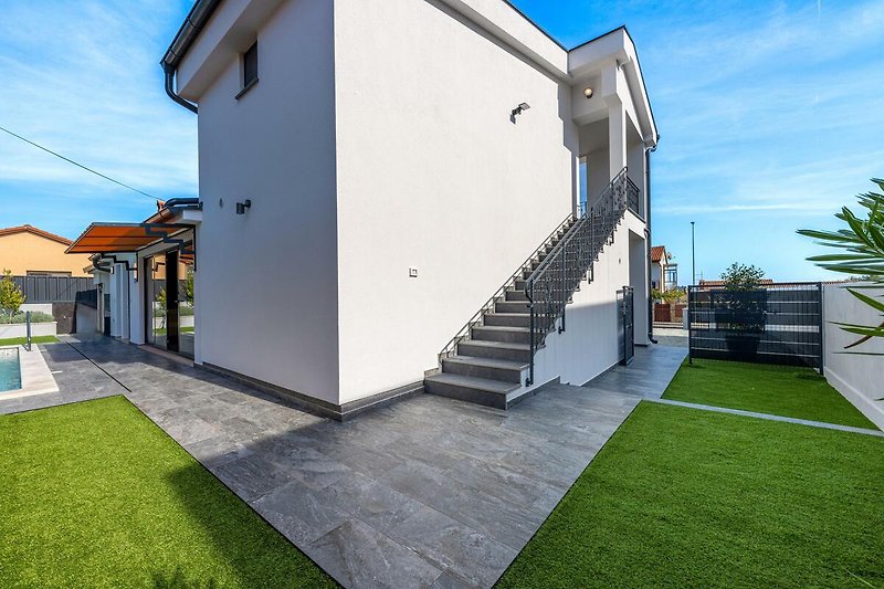 Schönes Haus mit modernem Design und stilvoller Fassade, umgeben von grüner Landschaft.