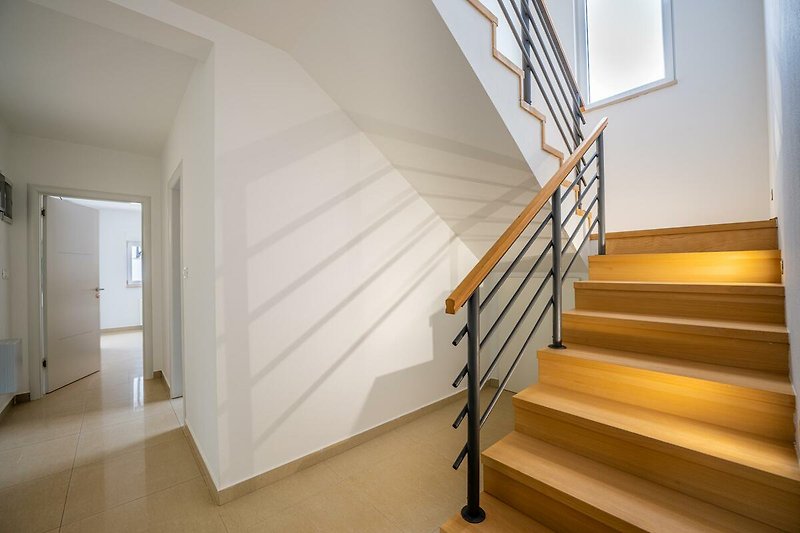 Willkommen in diesem stilvollen Haus mit Holzboden und modernem Design. Entspannen Sie auf der Treppe und genießen Sie den Raum.