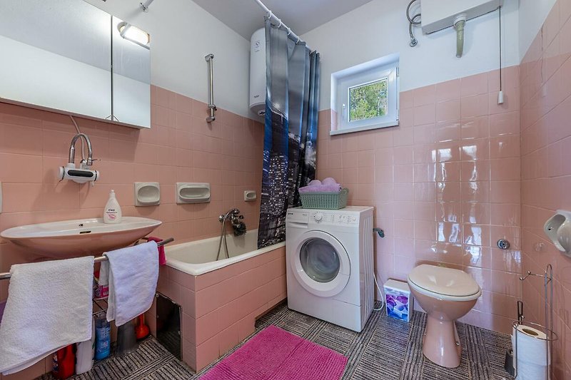 Ein modernes Badezimmer mit lila Waschbecken und Holzregal.