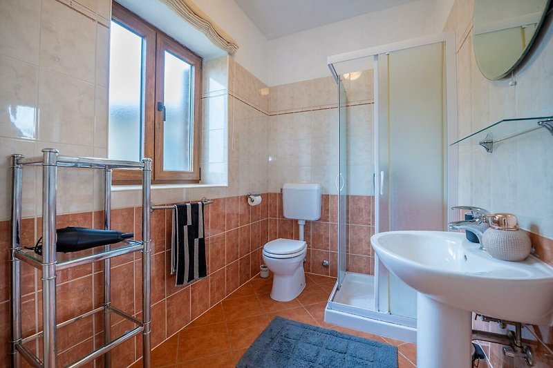 Gemütliches Badezimmer mit lila Akzenten und Holzdetails.