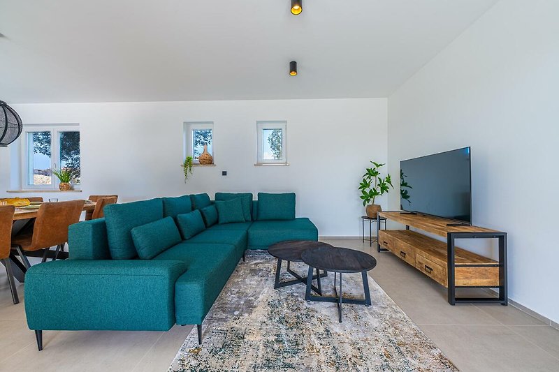 Wohnzimmer mit Couch, Tisch, Pflanze und Kunst.