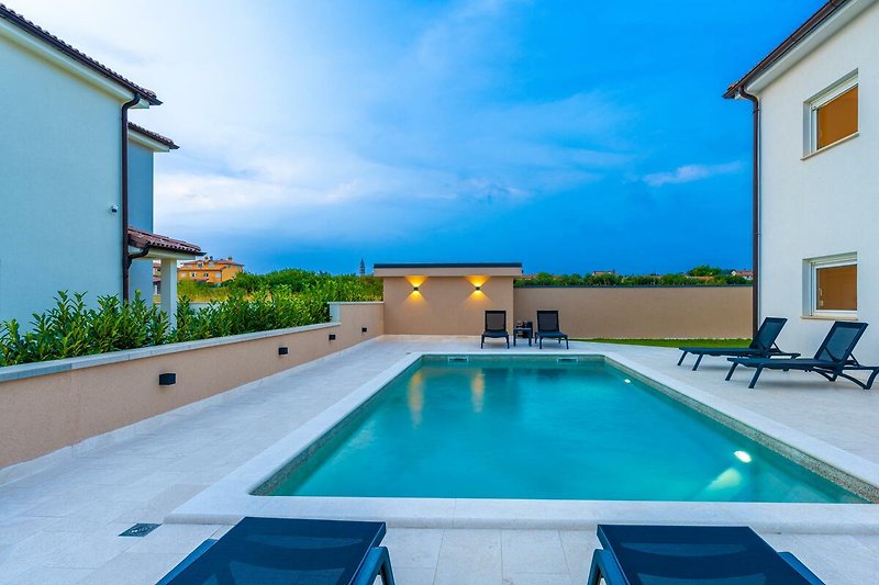 Entspannen Sie am Pool in diesem Ferienhaus mit herrlichem Blick auf das Wasser und den blauen Himmel.