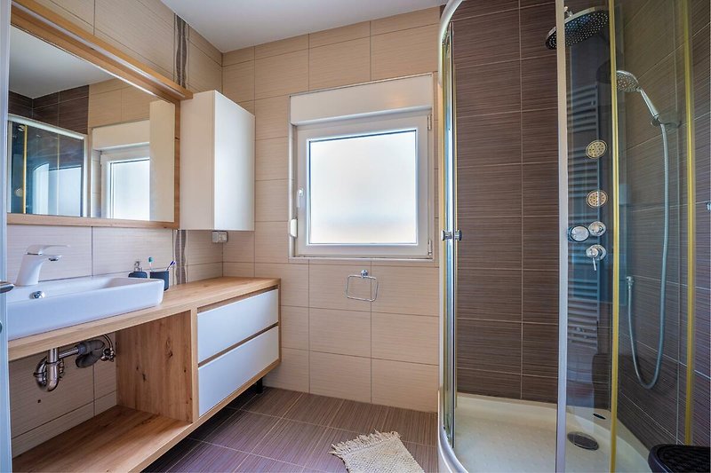 Entspannen Sie in diesem modernen Badezimmer mit stilvoller Einrichtung und hochwertigen Armaturen.