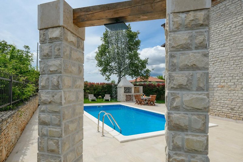 Luxuriöser Poolbereich mit Palmen, Garten und sonnigem Himmel.