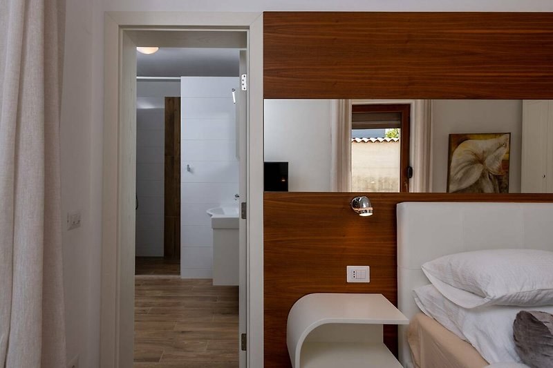 Gemütliches Schlafzimmer mit Holzmöbeln und Spiegel.