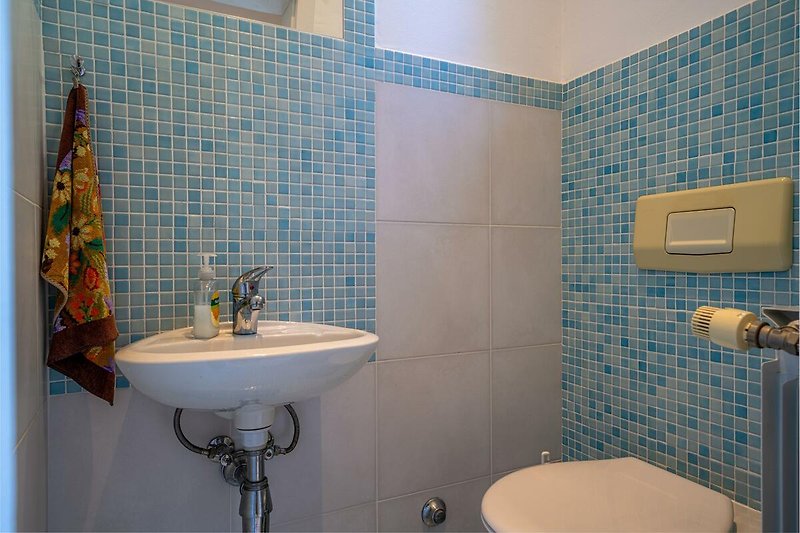 Badezimmer mit lila und blauen Fliesen, Waschbecken und Wasserhahn.
