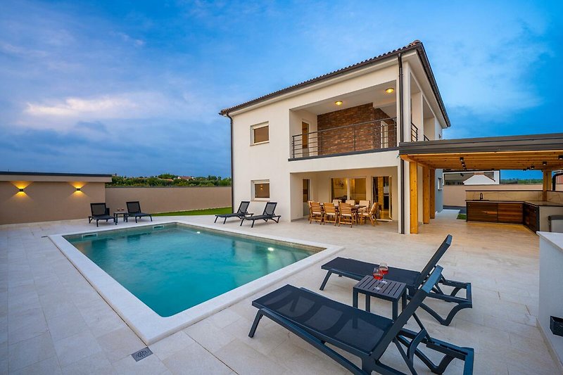 Entspannen Sie am Pool in diesem modernen Ferienhaus mit Blick auf den blauen Himmel und die umliegende Landschaft.
