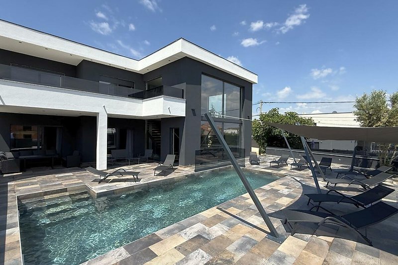 Villa mit Pool, Palmen und sonnigem Innenhof aus Beton.