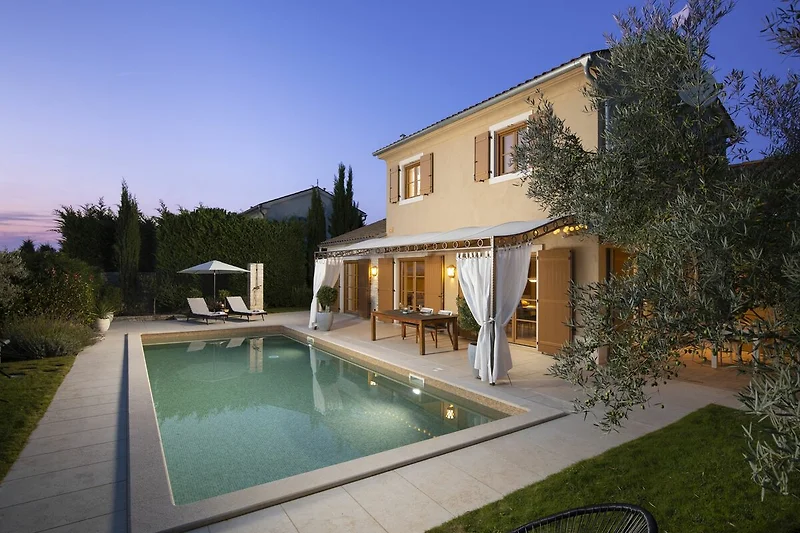 Villa mit Pool, großzügigem Patio, Gartenmöbeln und blühenden Pflanzen.