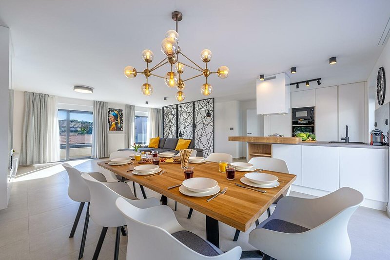 Moderne Küche mit elegantem Holztisch, Stühlen und stilvoller Beleuchtung.