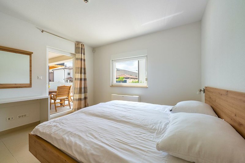Entspannen Sie in diesem komfortablen Schlafzimmer mit stilvollem Holzmobiliar und gemütlichem Bett. Genießen Sie die schöne Aussicht.