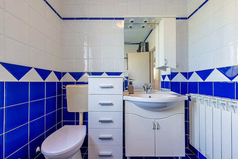 Gemütliches Badezimmer mit lila Fliesen, Spiegel und Waschbecken.