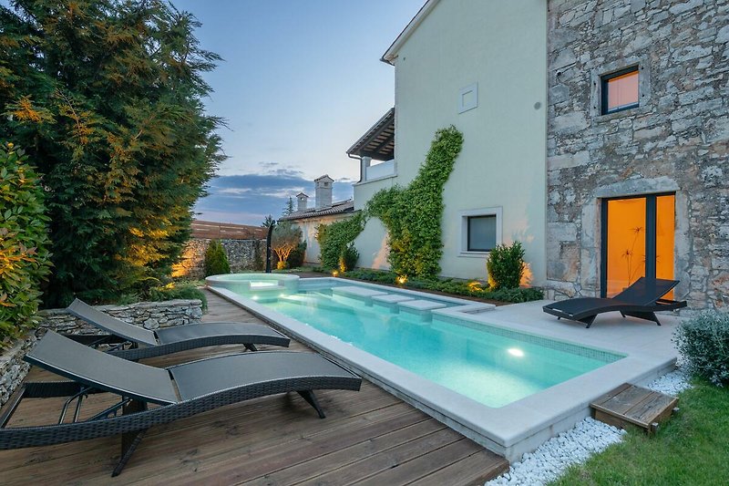 Luxuriöse Villa mit Pool, Garten, Sonnenliegen und moderner Einrichtung.