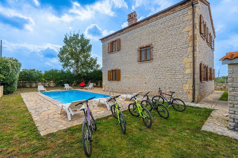Schönes Ferienhaus mit Fahrrädern vor blauem Himmel und grüner Landschaft.