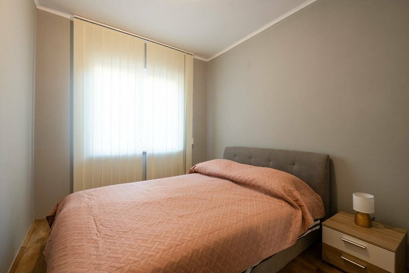 Gemütliches Schlafzimmer mit stilvollem Holzbett und schöner Fensterdekoration.