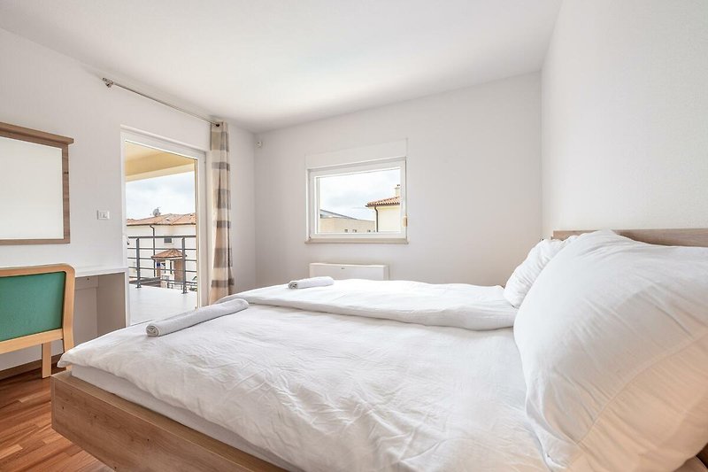 Willkommen in diesem komfortablen Schlafzimmer mit stilvollem Holzmobiliar und gemütlicher Beleuchtung. Genießen Sie den Ausblick aus dem Fenster.