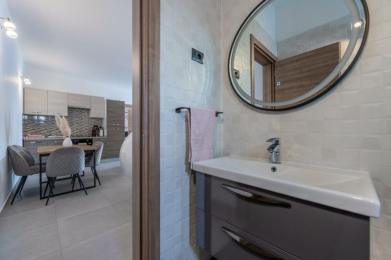 Schönes Badezimmer mit lila Möbeln und Holzboden.