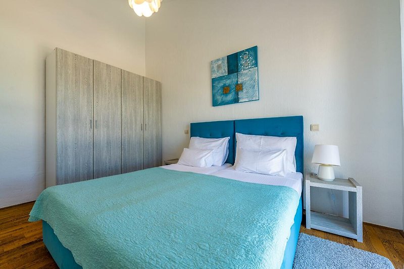 Gemütliches Schlafzimmer mit stilvollem Interieur und blauem Bett.