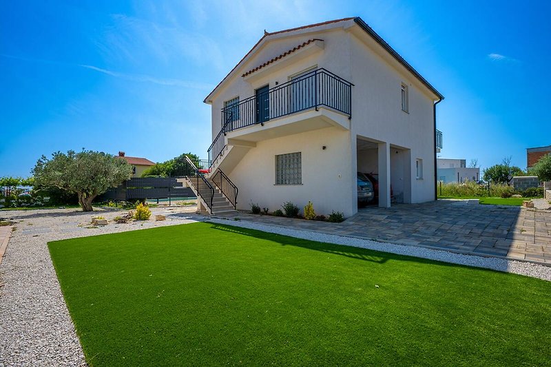 Schönes Haus mit grünem Garten und gepflegter Landschaft.