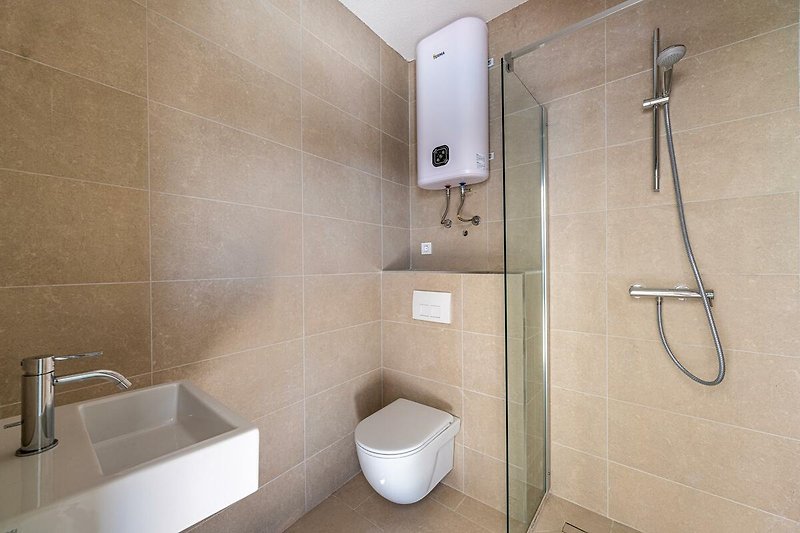 Modernes Badezimmer mit eleganter Armatur, Dusche und Spiegel.