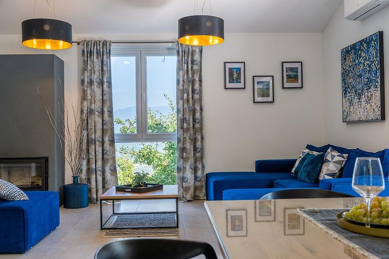 Gemütliches Wohnzimmer mit blauem Sofa, Pflanzen und warmem Licht.