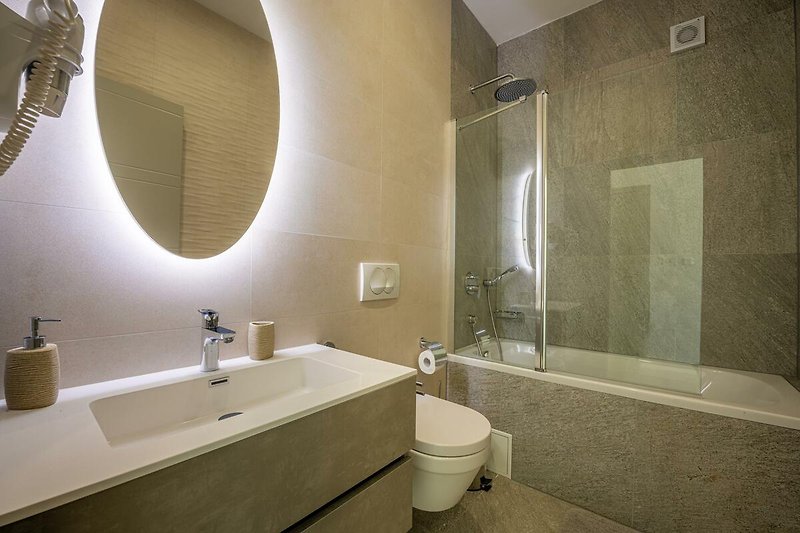 Schönes Badezimmer mit Spiegel, Wasserhahn und Duschkopf.