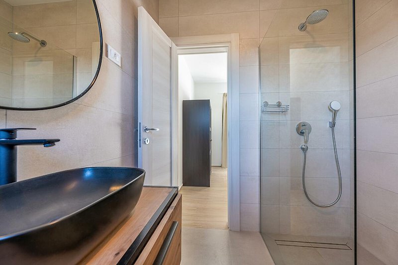 Modernes Badezimmer mit Dusche, Waschbecken und Glaswand.