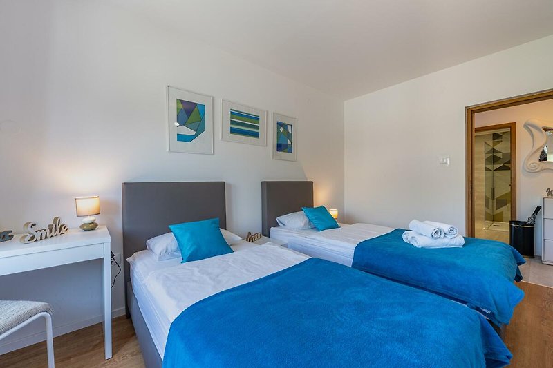 Gemütliches Schlafzimmer mit blauem Bett, Holzmöbeln und gemütlicher Beleuchtung.