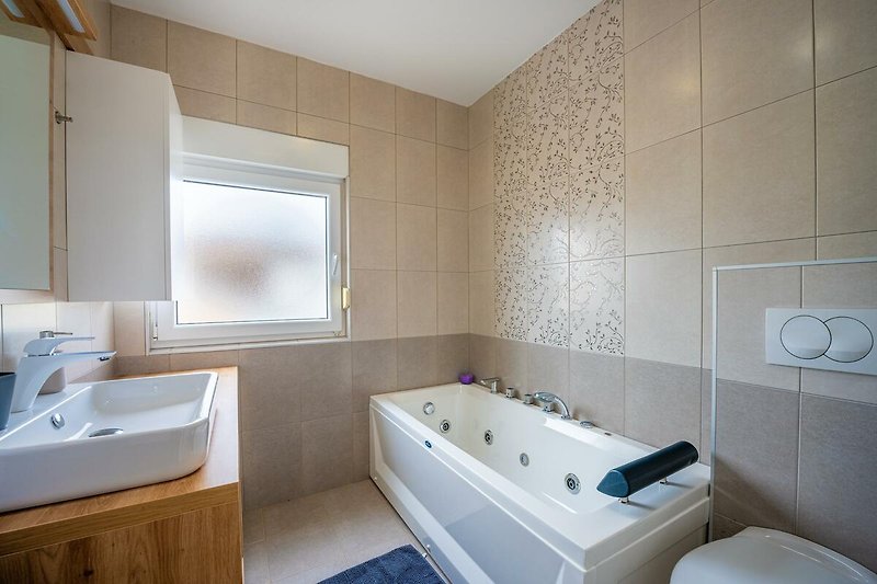 Willkommen in diesem stilvollen Badezimmer mit modernen Armaturen. Entspannen Sie in der Badewanne und genießen Sie den Komfort.