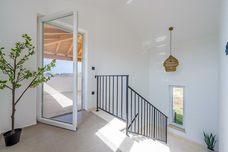 Elegante Treppe mit Holzgeländer und Glasfenster.