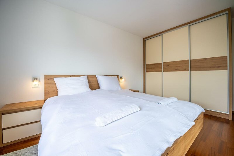 Willkommen in diesem stilvollen Schlafzimmer mit hochwertigem Mobiliar und gemütlichem Bett. Entspannen Sie und genießen Sie die schöne Aussicht.