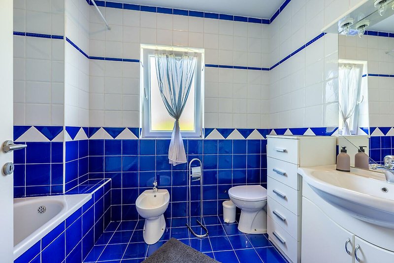 Gemütliches Badezimmer mit lila Fliesen, Spiegel und Waschbecken.