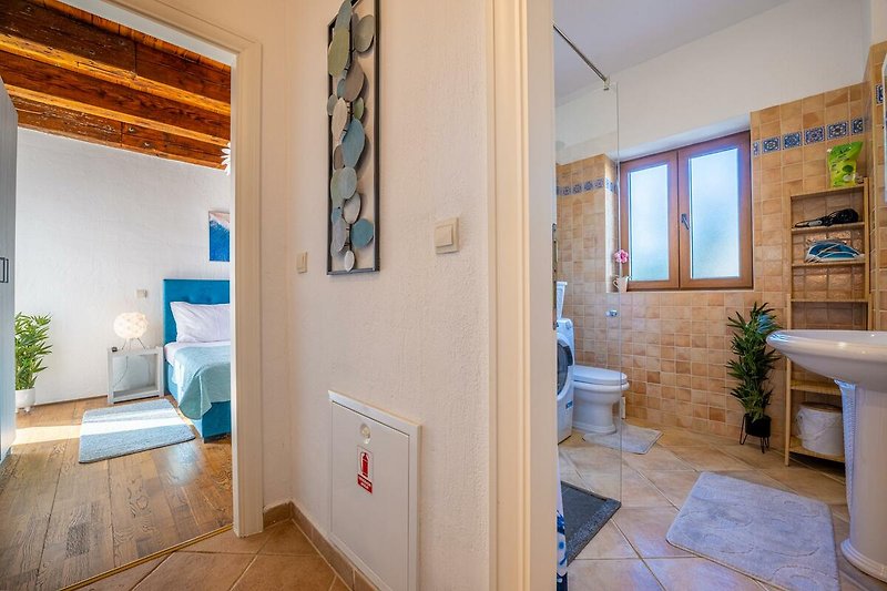 Stilvolles Badezimmer mit blauem Vorhang, Holzboden und Spiegel.