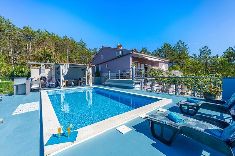 Schwimmbad mit Sonnenliegen und Sonnenschirmen in einer Ferienanlage.
