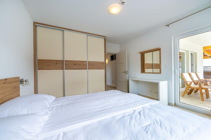 Entspannen Sie in diesem komfortablen Schlafzimmer mit stilvollem Holzmobiliar und gemütlicher Beleuchtung. Genießen Sie den Ausblick aus dem Fenster.