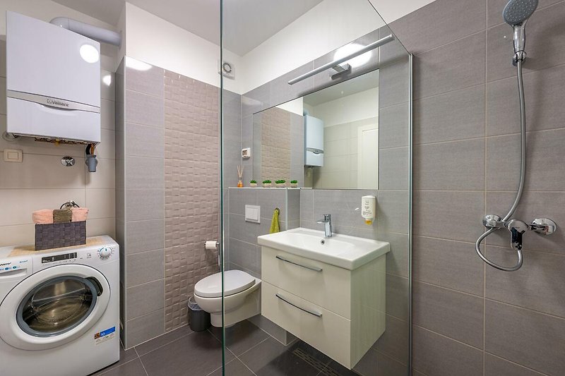 Modernes Badezimmer mit Dusche, Waschbecken und Spiegel.
