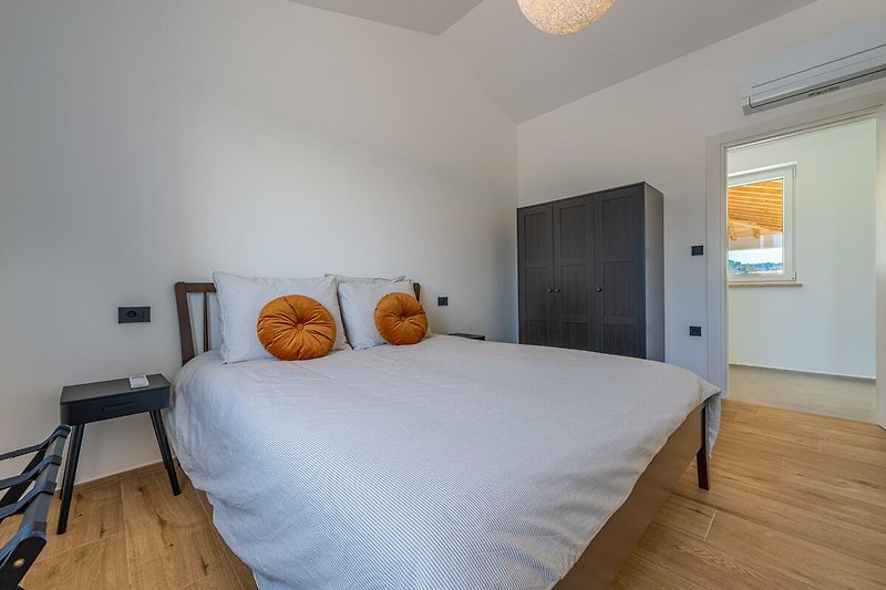 Modernes Schlafzimmer mit Holzmöbeln und orangefarbenen Akzenten.