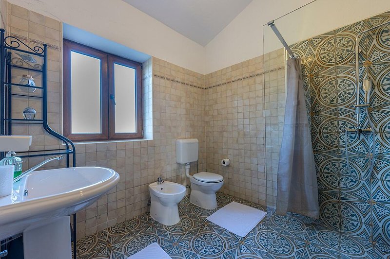 Schönes Badezimmer mit lila und blauen Fliesen und Spiegel.