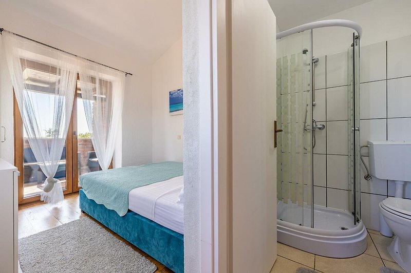 Gemütliches Badezimmer mit Fenster, Vorhang und Holzboden.