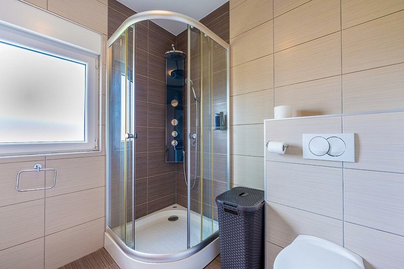 Entspannen Sie in diesem modernen Badezimmer mit lila Akzenten. Genießen Sie eine erfrischende Dusche oder ein entspannendes Bad.