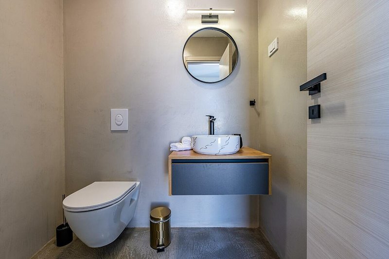 Schönes Badezimmer mit lila Waschbecken und Holzboden.