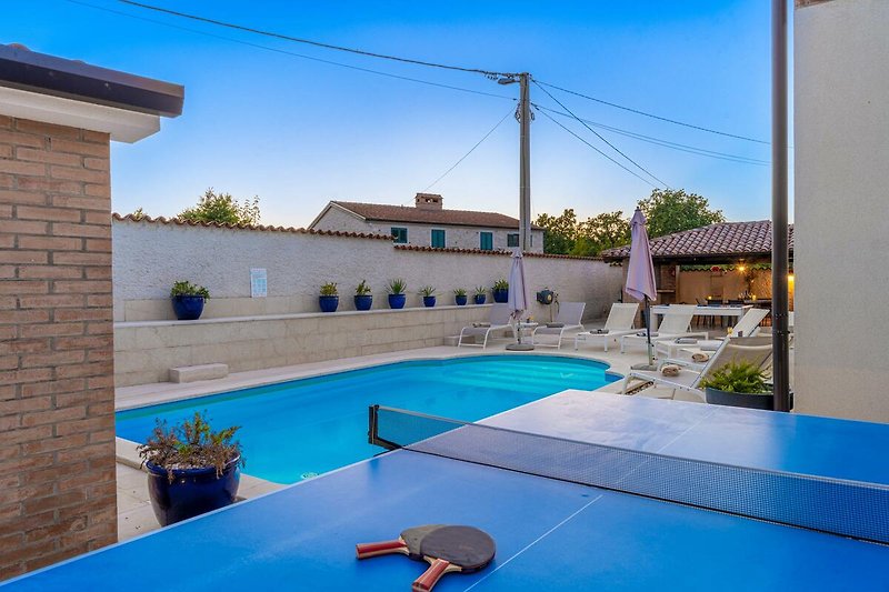Schönes Ferienhaus mit Pool, blauem Wasser und gemütlicher Außenmöblierung.