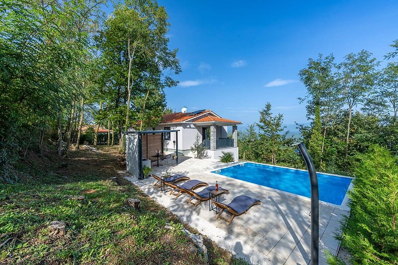 Ein charmantes Haus mit einem grünen Garten und einem schönen Blick auf die Landschaft.